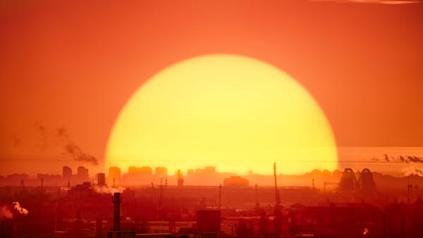 een ondergaande zon achter een industriegebied