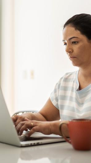 Vrouw typt op een laptop met serieuze blik
