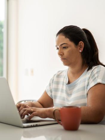 Vrouw typt op een laptop met serieuze blik