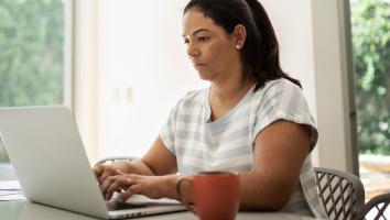 Vrouw typt op een laptop met serieuze blik