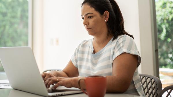 Vrouw typt op een laptop met serieuze blik