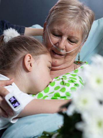 een kleindochter knuffelt haar zieke oma