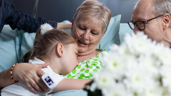 een kleindochter knuffelt haar zieke oma