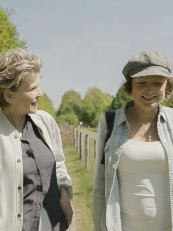 Anita Witzier wandelend met Hedwig langs bomen en een weiland
