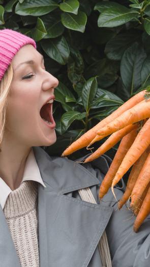 iemand kijkt met open mond naar een bos wortels in haar hand