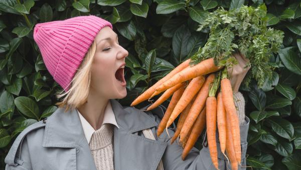 iemand kijkt met open mond naar een bos wortels in haar hand