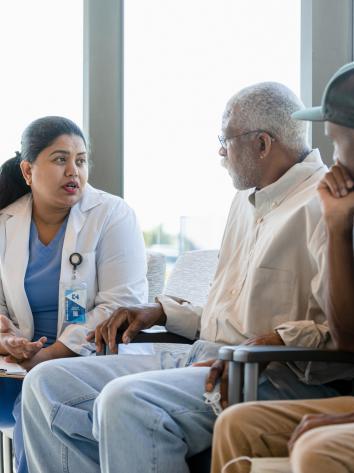 Verpleegkundige in uniform in gesprek met vader en zoon in wachtkamer