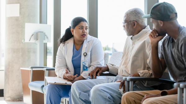 Verpleegkundige in uniform in gesprek met vader en zoon in wachtkamer