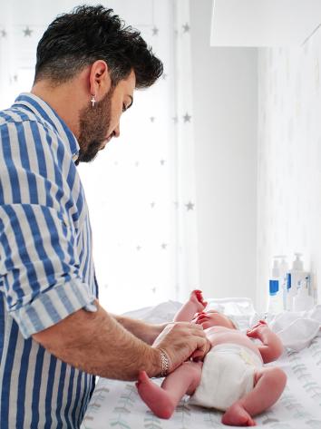 een man verschoont de luier van zijn baby