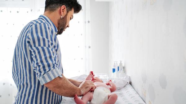 een man verschoont de luier van zijn baby