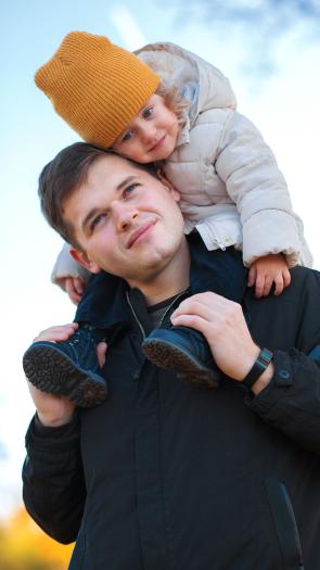 een vader met zijn kind op zijn nek