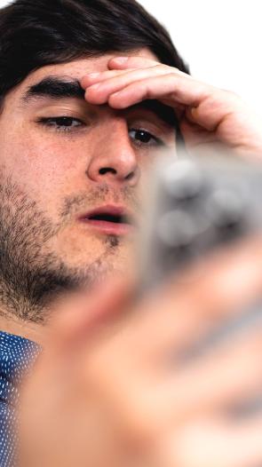 een man kijkt geschokt naar iets op zijn telefoon