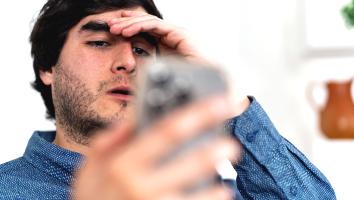 een man kijkt geschokt naar iets op zijn telefoon