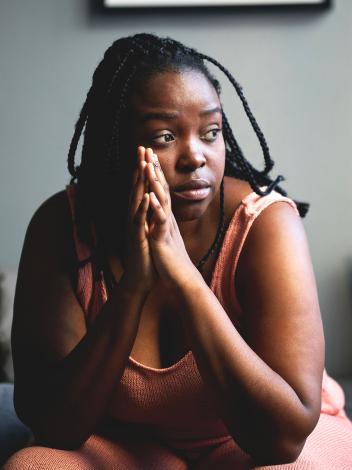 een vrouw staart voor zich uit met haar handen ineen gesloten