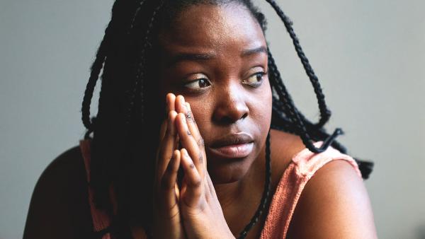 een vrouw staart voor zich uit met haar handen ineen gesloten