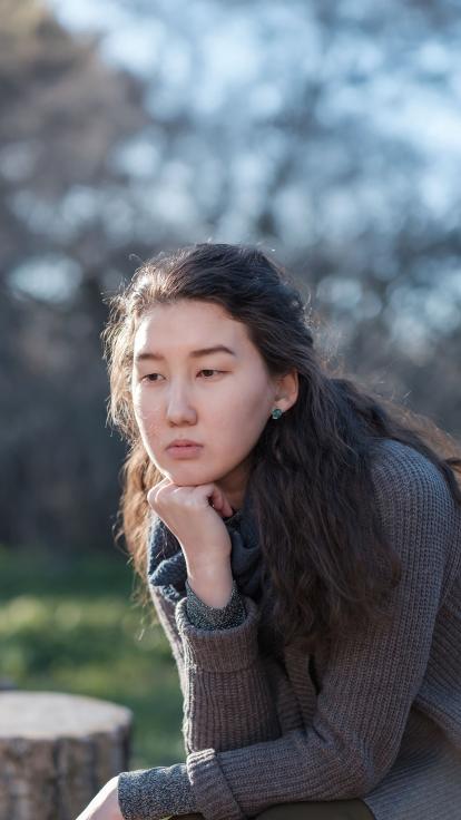 Foto van een somber voor zich uit starende vrouw.