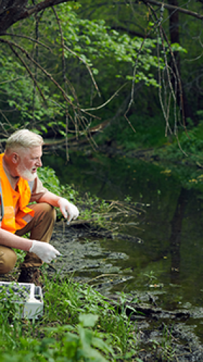 Bioloog doet onderzoek naar water in riviertje.