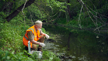 Bioloog doet onderzoek naar water in riviertje.