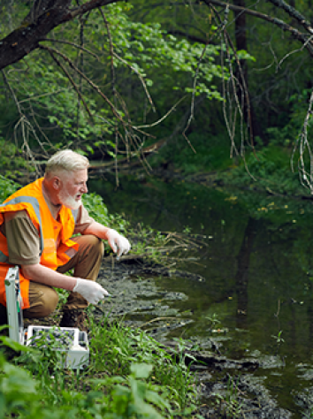 Bioloog doet onderzoek naar water in riviertje.