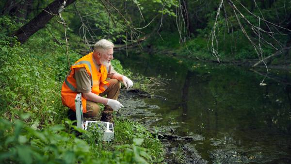 Bioloog doet onderzoek naar water in riviertje.