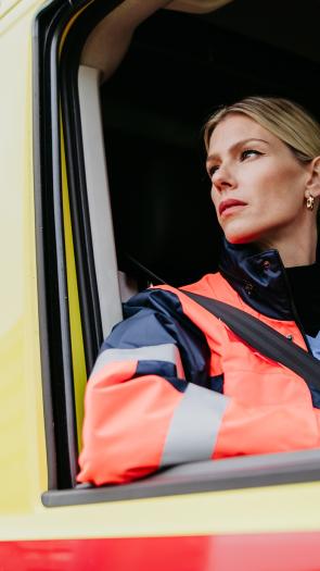 Ambulancemedewerkster kijkt uit het raam van de ambulance.