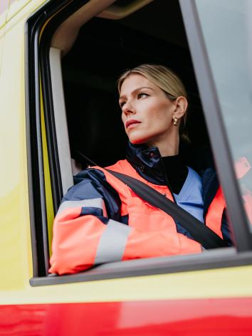 Ambulancemedewerkster kijkt uit het raam van de ambulance.