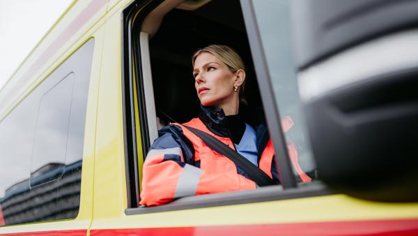 Ambulancemedewerkster kijkt uit het raam van de ambulance.