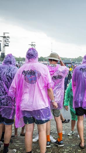 Festivalgangers lopen door de regen op weg naar een concert.