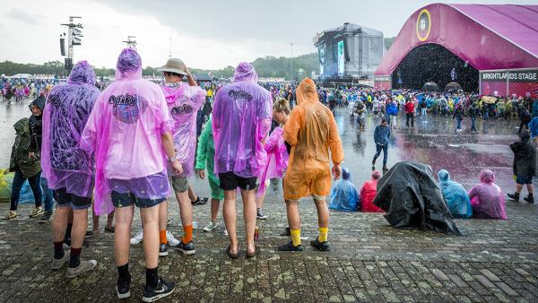 Festivalgangers lopen door de regen op weg naar een concert.