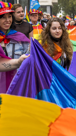 Mensen vieren Gay Pride in Amsterdam met regenboogvlaggen en vrolijke kleding.