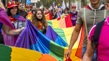 Mensen vieren Gay Pride in Amsterdam met regenboogvlaggen en vrolijke kleding.