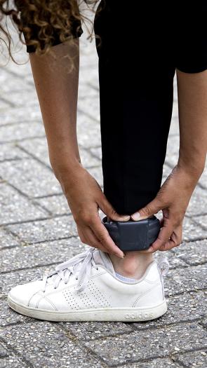 Vrouw bukt voorover en pakt haar enkelband vast