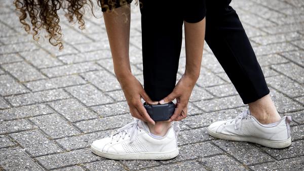 Vrouw bukt voorover en pakt haar enkelband vast