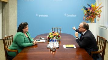 Verkenner Koolmees zit met Caroline van der Plas aan houten tafel in gesprek bij muur waar Tweede Kamer op staat
