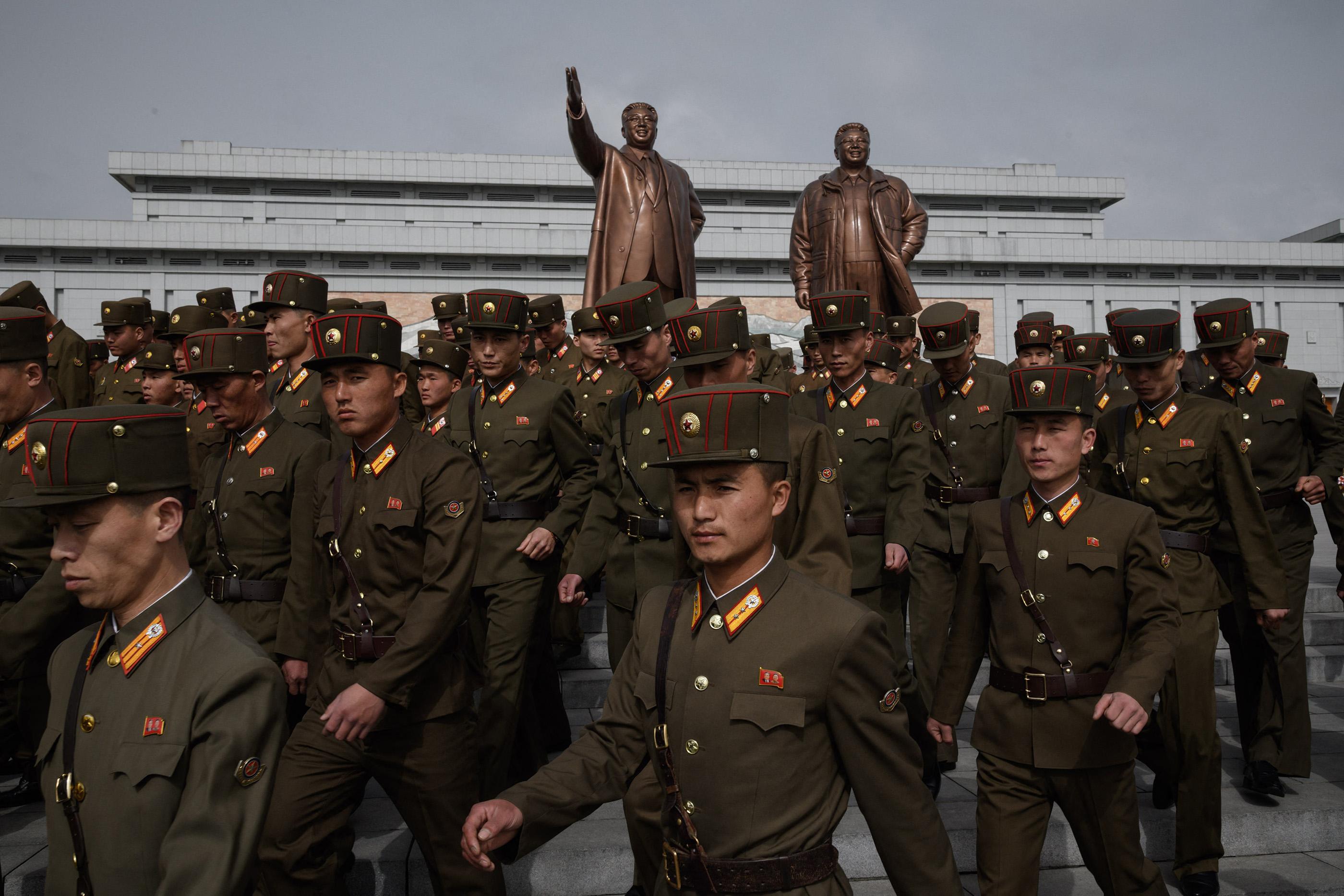 Soldaten lopen langs de standbeelden van Kim Jong-uns voorgangers