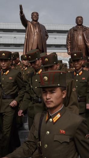 Soldaten lopen langs de standbeelden van Kim Jong-uns voorgangers