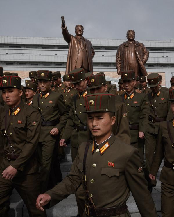 Soldaten lopen langs de standbeelden van Kim Jong-uns voorgangers