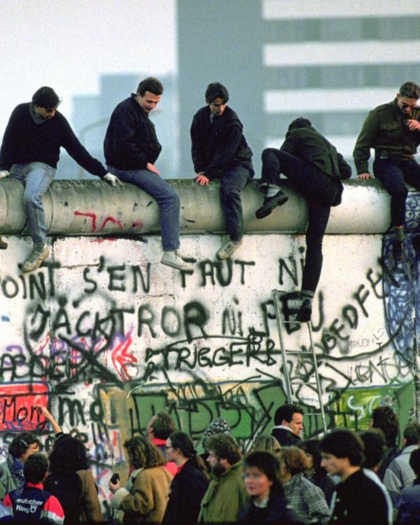 Jongeren zitten op de Berlijnse Muur tijdens de val van de muur.
