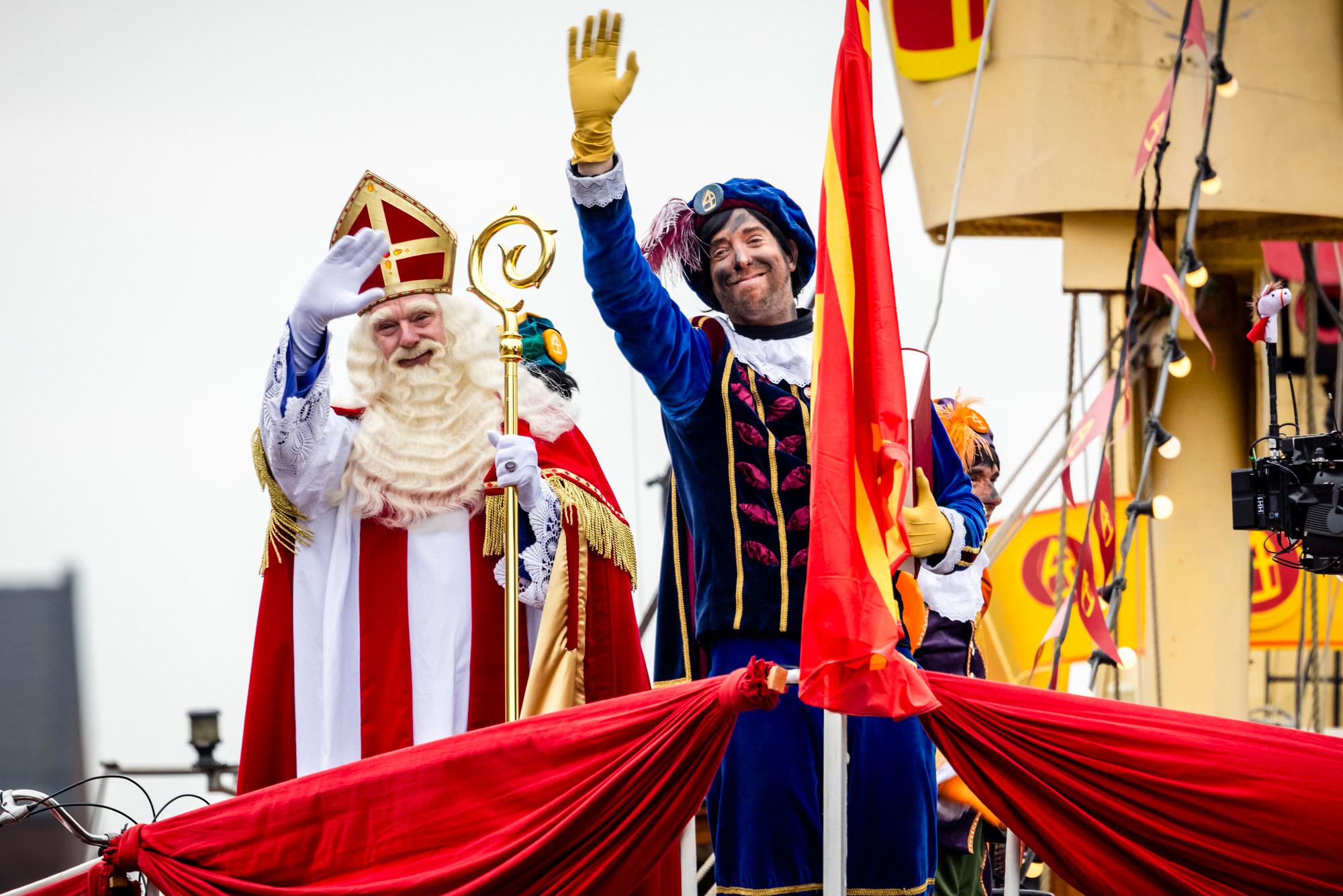 Een foto van Sinterklaas en roetveegpiet die vanaf de pakjesboot zwaaien.