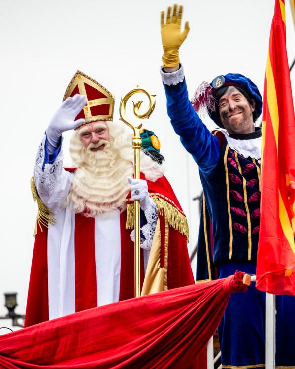 Een foto van Sinterklaas en roetveegpiet die vanaf de pakjesboot zwaaien.