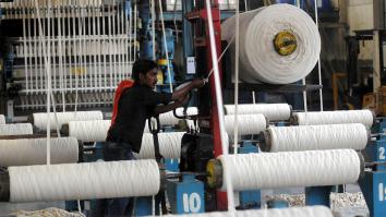 Man tussen enorme rollen met draad is garen aan het spinnen