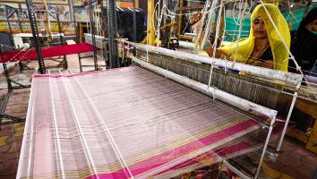 Gesluierde vrouw achter weefmachine maakt van veel dunne draden een stof