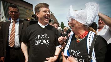 Premier Jan Peter Balkenende trekt lachend een T-shirt aan met de tekst 'Fuck drugs'. Naast hem een actievoerder in traditionele Volendamse klederdracht met hetzelfde shirt erbij aan.
