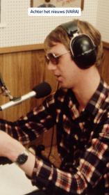 Een radiopiraat uit de jaren 80 spreekt in de microfoon en heeft een koptelefoon op. 