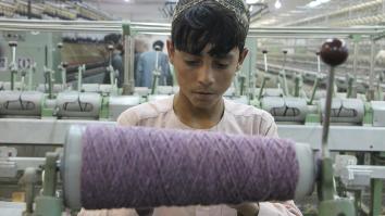 Jongen achter rol met garen in textielfabriek