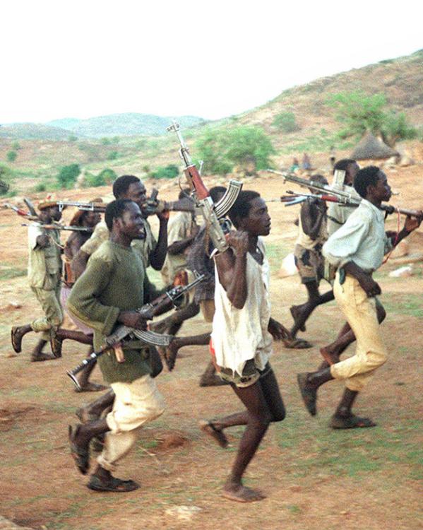 Rennende mannen met vuurwapens door een grasvlakte