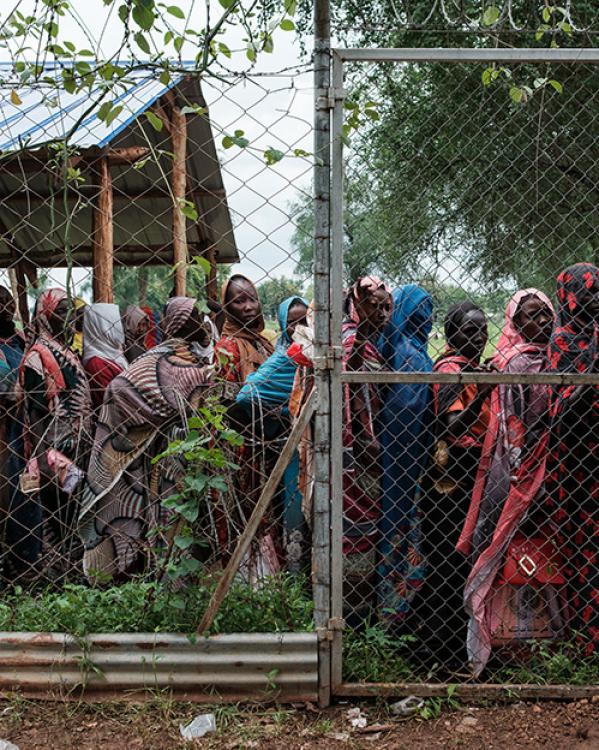 Vrouwen achter een hek in de rij voor eten