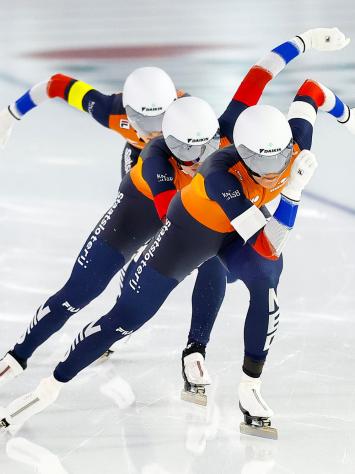 Drie Nederlandse schaatsers sprinten samen achter elkaar over de ijsbaan