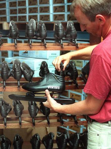 Een verkoper houdt een klapschaats vast voor de camera, met op de achtergrond meer vergelijkbare schaatsen.