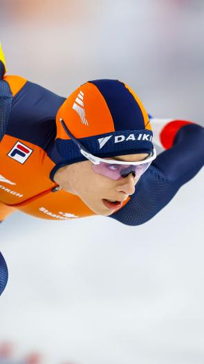 Een close-upfoto van schaatser Femke Kok die geconcentreerd aan het schaatsen is in een wedstrijd